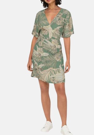 Vestido de manga corta en tejido verde con un estampado de hojas y flores tropicales, con escote en V y corte relajado.