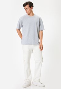 Grå kortærmet t-shirt med rund hals, parret med hvide cargo bukser med sidelommer og hvide sneakers. Enkel og afslappet design.