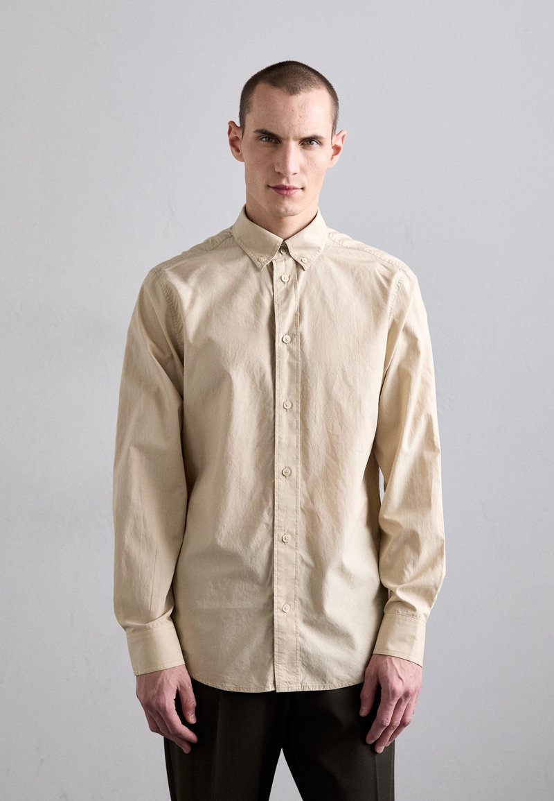 Beige skjorte med knapper, lange ærmer, krave og et afslappet fit. Lavet af letvægtsstof med en subtil tekstur og en glat finish.