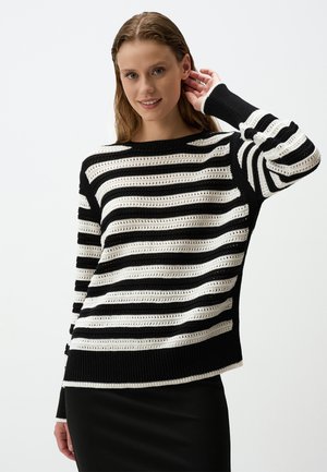 Maglione a strisce bianco e nero in maglia con texture a rete aperta, polsini a costine e scollatura arrotondata. Vestibilità ampia, design casual adatto per essere indossato a strati.