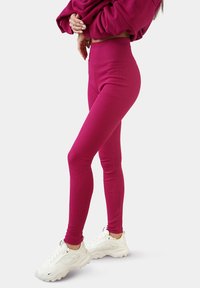 Strakke roze leggings gemaakt van rekbaar materiaal, met een hoge tailleband, gecombineerd met witte sportschoenen.
