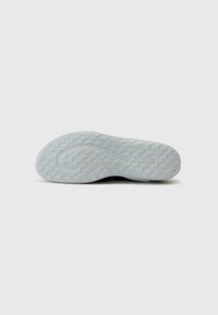 Sole di sneaker nera con un pattern in gomma grigia chiara testurizzata; presenta un design curvilineo per aderenza e flessibilità.