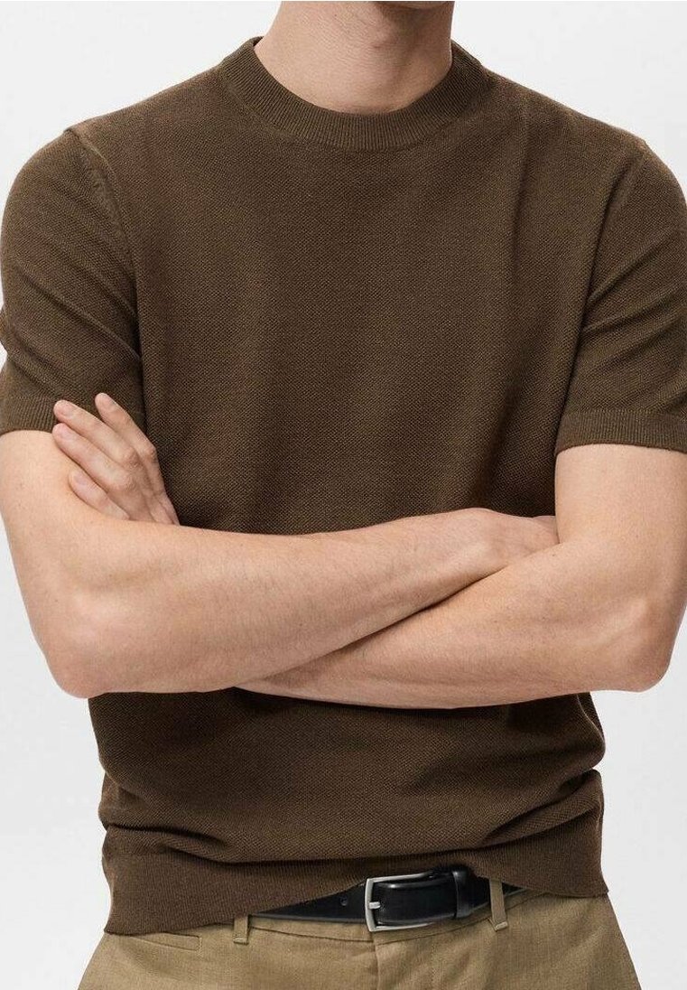Maglione corto a maniche corte di colore marrone con scollatura rotonda, caratterizzato da un tessuto testurizzato e una vestibilità slim. Abbinato a pantaloni in tonalità neutre e una cintura nera.