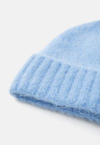 Light blue wool beanie with a soft, fuzzy texture and ribbed cuff detail. The top is rounded, providing a snug fit.
