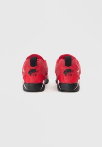 Rote Sportschuhe mit einer strukturierten Oberseite, schwarzen Akzenten und sichtbarem Markenlogo. Das Design verfügt über eine Ziehschlaufe und eine gepolsterte Sohle.