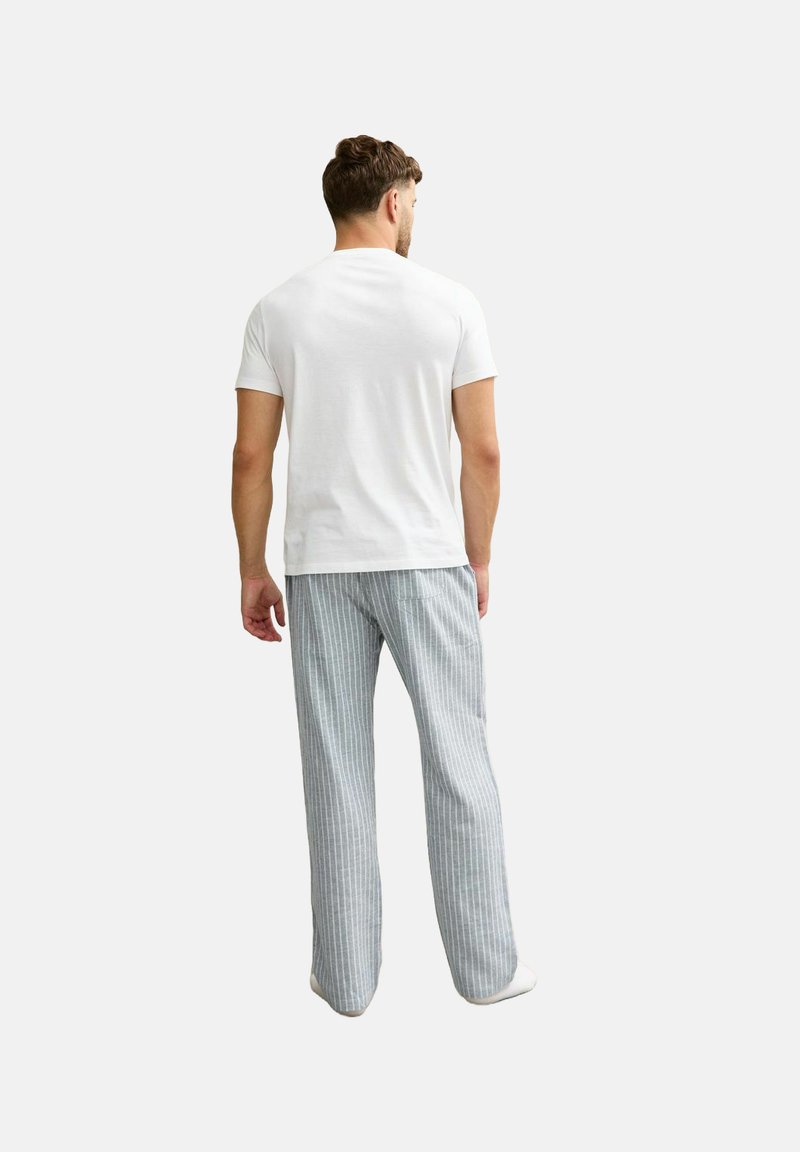 Camiseta blanca de manga corta combinada con pantalones de pijama a rayas en gris claro y blanco, con un ajuste relajado y tela suave.