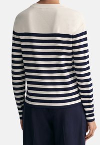 Gestreifter Pullover mit navyblauen und cremefarbenen horizontalen Streifen, aus weichem Material gefertigt, mit Rundhals und eng anliegenden langen Ärmeln.