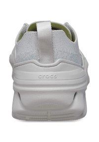 White athletic shoe with a textured fabric upper, padded collar, and pull tab. Features a thick, cushioned sole with grooves for traction.