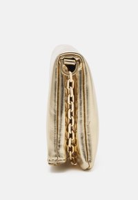 Pochette métallique dorée pliée avec une bandoulière chaîne dorée vue de côté sur fond blanc uni.
