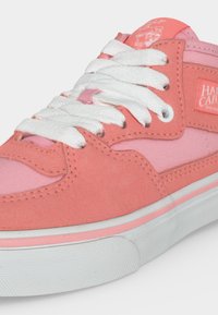 Baskets roses et corail avec lacets blancs, semelle texturée et étiquette de marque visible sur le côté et la languette.