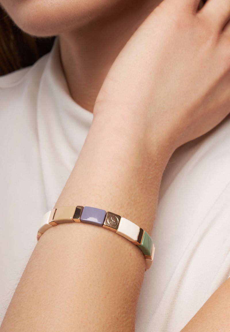 Bunter Armreif mit abwechselnden rechteckigen Gliedern in Beige, Lavendel, Weiß, Grün und goldfarbigen Akzenten. Glatte Oberfläche, modernes Design.