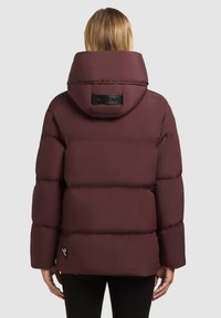 Chaqueta acolchada burdeos con capucha, que presenta un logo en la parte posterior, textura acolchada y un corte relajado. Incluye una etiqueta de acento negra.