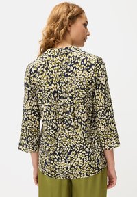 Langarmbluse mit einem abstrakten Muster in Marineblau, Grün und Creme, ausgestattet mit einem Kragen und einer Rückenpasse, aus leichtem Stoff gefertigt.