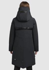 Manteau rembourré noir avec un col montant et une capuche, présentant une sangle de marque dans le dos, une texture lisse et un ourlet en biais.