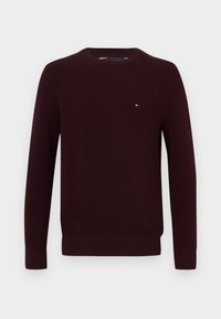 Pull bourgogne avec un col rond, des manches longues, des poignets côtelés et un petit logo sur la poitrine. Fabriqué en tissu tricoté texturé.