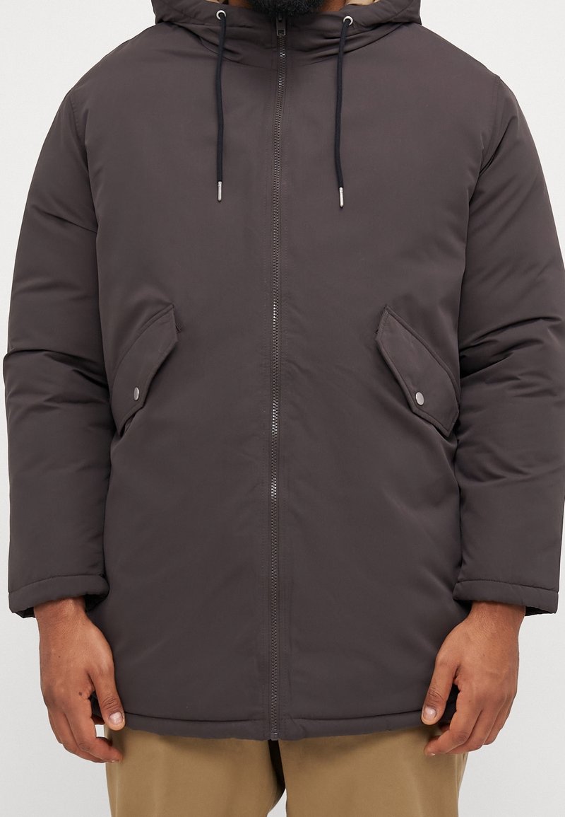 Cappotto imbottito grigio scuro con cappuccio, chiusura con zip e due tasche laterali. Presenta polsini elasticizzati e una superficie liscia.