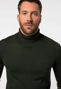 Maglione a collo alto verde scuro in tessuto a maglia liscia, con colletto alto e design aderente, senza motivi o decorazioni visibili.
