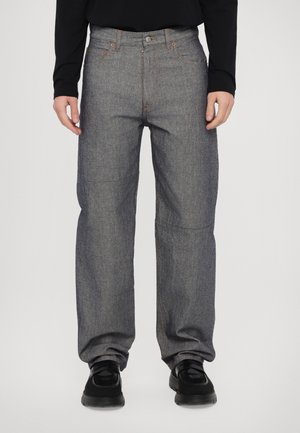 Dark denim trousers with a straight-leg design, featuring orange stitching and a button closure. Material has a textured, durable appearance.