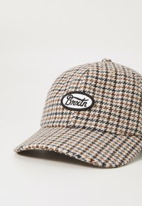 Houndstooth-mustriga müts, mille toonid on beež, pruun ja tumesinine. Esifoorumil on must ovaalne pannal, millel on valge tekst "Brixton".