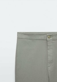 Pantalons gris clair en tissu lisse, dotés d'une taille droite avec une fermeture à un bouton unique et de détails de couture subtils.