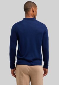 Granatowa koszulka polo z długim rękawem, kołnierzykiem, teksturowaną tkaniną i dopasowanym krojem. Posiada rękawy typu raglan oraz gładki dół.