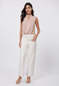 Top sin mangas de color rosa claro con un detalle en forma de ojo de cerradura, combinado con pantalones de pierna ancha blancos. El conjunto presenta una textura suave y lisa.