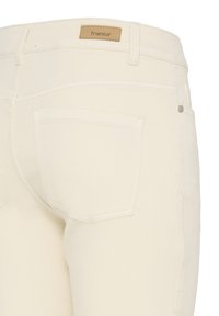 Hvide denimjeans med talje i midjehøjde, baglomme og en tanfarvet mærkeetiket syet fast i linningen. Subtile syningsdetaljer er synlige.