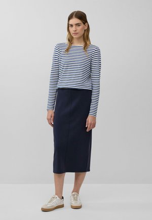 Prugasta bluza z dolgimi rokavi v mornarsko modri in beli barvi, v kombinaciji z mornarsko modrim midi krilom. Beli športni copati z bež detajli. Enostavna in oprijeta silhueta.