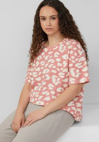 Rosa Kurzarmoberteil mit weißem Leopardenmuster, aus weichem Stoff; lockere Passform mit rundem Ausschnitt und umgeschlagenen Ärmeln.