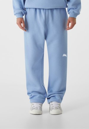 Hellblaue Jogginghosen mit elastischem Bund und Bündchen, versehen mit einem kleinen weißen Logodetail. Hergestellt aus weichem, glattem Stoff.