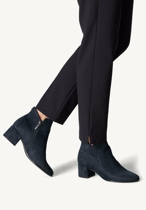 Sorte ruskind ankle boots med blok hæle, båret med sorte skræddersyede bukser med ankelslids.