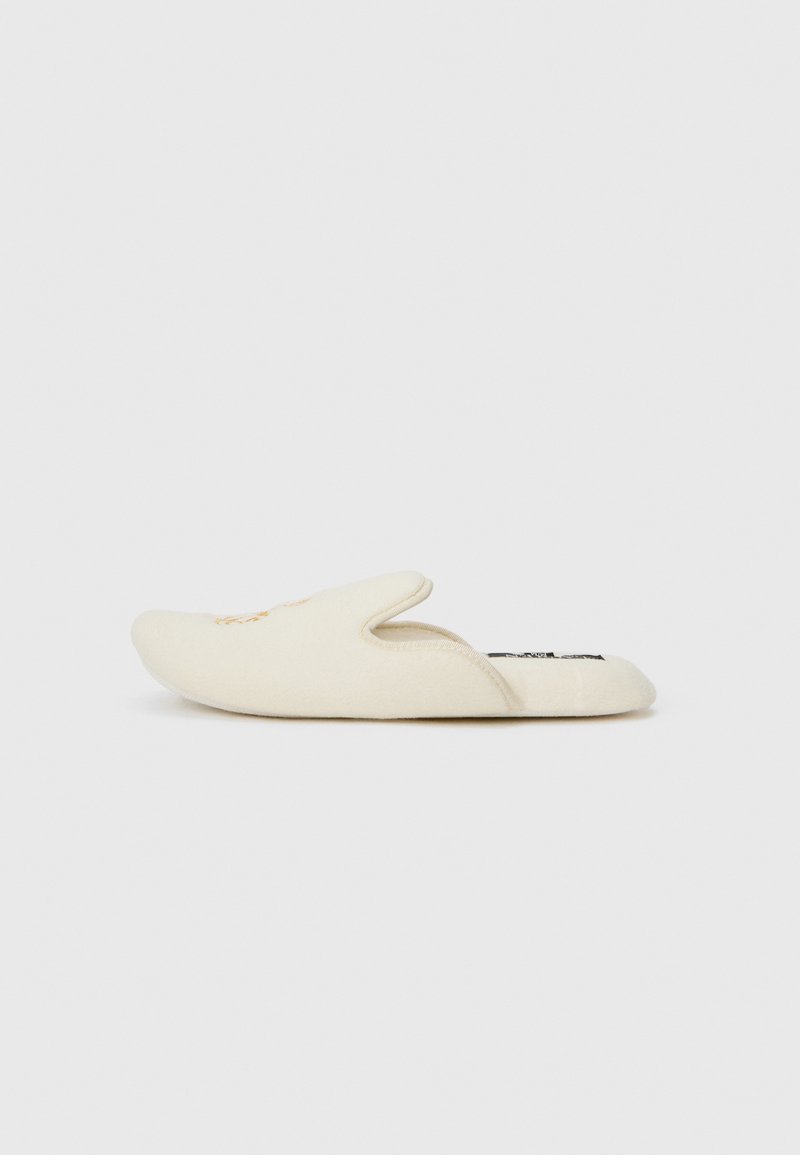Pantofii slip-on de culoare crem, cu vârful rotund și spate deschis. Material moale din țesătură cu un design minimalist, fără modele distincte sau accesorii metalice.
