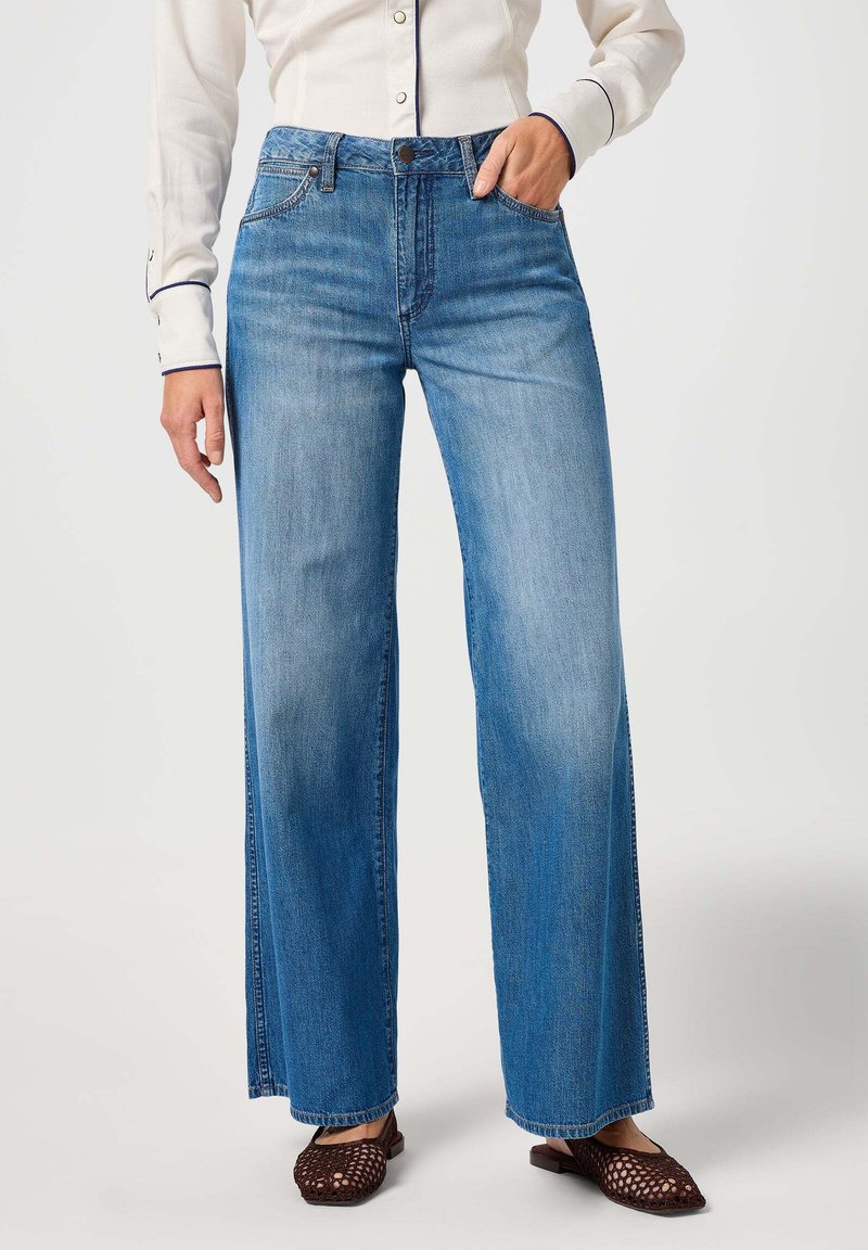 Jeans de pernera larga em azul claro, feitos em denim, com uma cintura alta, bolsos laterais e um corte reto com um leve desbotado.