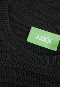 Musthave mustre paelakäedega. Roheline brändi silt valge tekstiga "JJXX" kaela all.