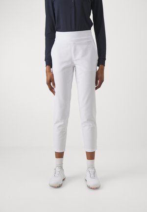 Weiße, taillierte Hosen mit glatter Textur, hohem Taillenbund und schmal zulaufendem Bein, kombiniert mit einem navyfarbenen Langarmshirt und weißen Sneakers.
