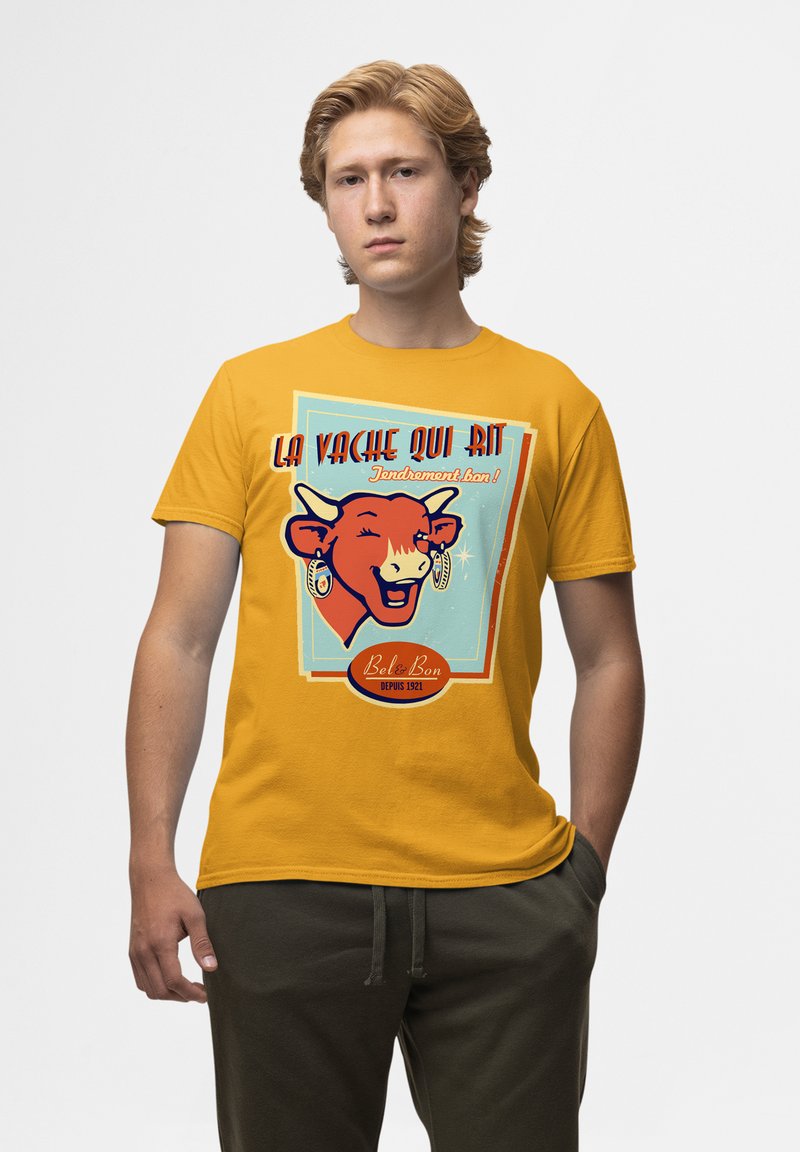 Žluté bavlněné tričko s grafikou usmívající se krávy. Text zní "La Vache Qui Rit" v červené a modré barvě, s dekoračními prvky a vintage stylem.