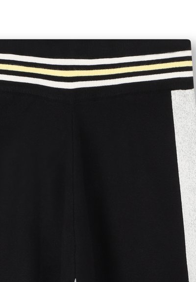 Zwarte broek met een witte en gele gestreepte elastische tailleband en witte zijpanelen, zichtbaar zijn het bovenste deel van de taille en een deel van het beengebied.
