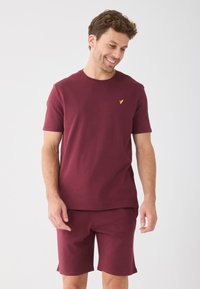 Bordeaux bomuld t-shirt med rund hals, korte ærmer og et lille guld logo på venstre bryst; parret med matchende shorts.