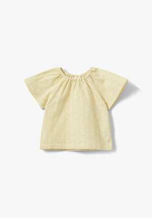 Blusa gialla crema a maniche corte con scollo rotondo elastico e motivo ricamato a fiori traforati sul tessuto.