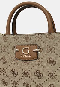 Sac à main beige à motif avec des accents en cuir marron, affichant un logo "G" doré et une plaque de marque à l'avant. Poignées à double boucle.