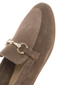 Mocassini in suede marrone con punta tonda, caratterizzati da un accento dorato con strass e cuciture visibili lungo i bordi.