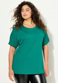T-shirt teal oversize con maniche corte e arricciate. Realizzato in tessuto morbido, presenta un collo rotondo e una vestibilità comoda.
