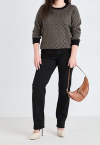 Pull en tricot avec un motif en zigzag, pantalon noir et sac à épaule en simili cuir marron. Des talons compensés beiges complètent le look.