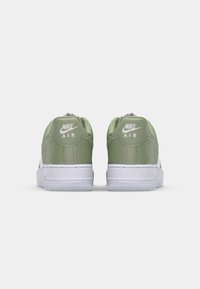 Grønne Nike Air sneakers har et glat skaft, hvid sål og branding på hælen. Rundet design med en polstret krave for komfort.