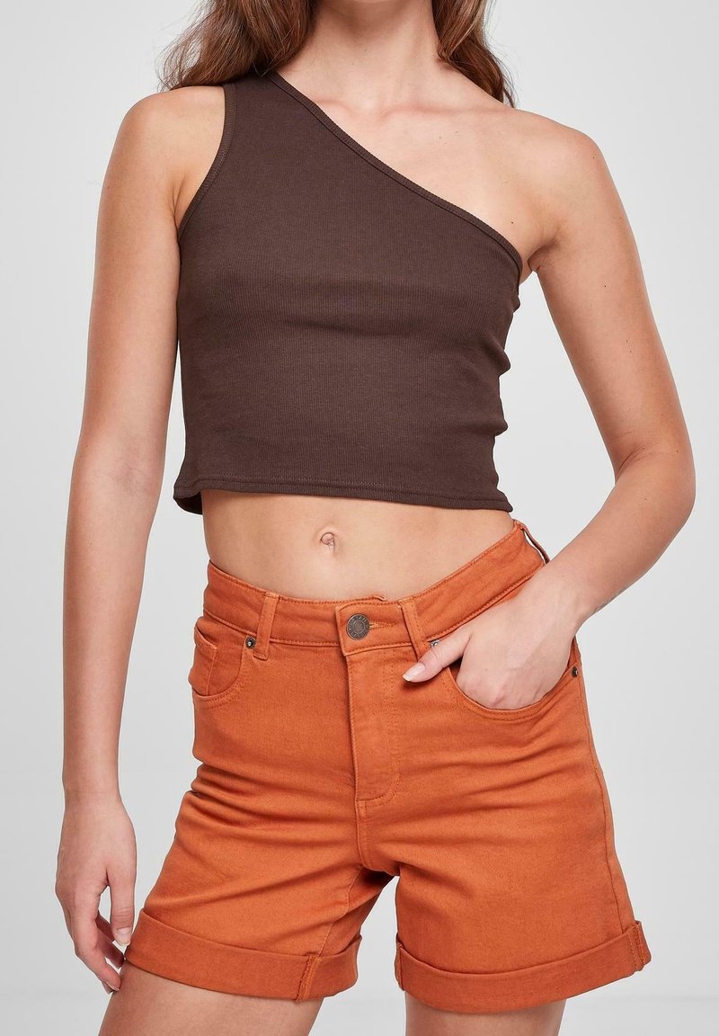 Top corto de un solo hombro en tela de canalé marrón, combinado con pantalones cortos de denim naranja de cintura alta con dobladillo enrollado y bolsillos delanteros.