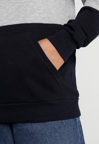 Felpa con cappuccio blu navy e grigia, dotata di tasca a marsupio, polsini a costine e finitura testurizzata, che mette in risalto il tessuto morbido in misto cotone.