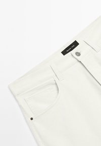 Bílé džínové kalhoty s knoflíkovým zapínáním, jednou zadní kapsou a štítkem se znakem "Massimo Dutti" na pasu.