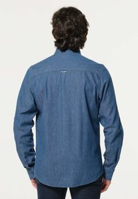 Denim overhemd in een middentoon blauw, met een button-down kraag, lange mouwen en een gebogen zoom. Subtiele stiksels aan de achterkant.