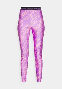 Lila leggings med en glänsande yta, mönstrade med stor rosa text "Versace Jeans Couture" och en svart elastisk midja.
