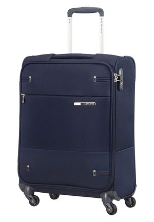Valigia blu navy con esterno in tessuto testurizzato, quattro ruote, manico estensibile e tasca frontale con zip. Presenta elementi di branding e dettagli in metallo.